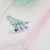 Illustration of a stitched, greenish hand with black nails, resembling a monster or zombie hand, on a white surface. Surrounding the illustration are parts of pastel-colored fluffy pens in mint green and pink.